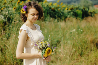 stylish gorgeous rustic bride with bouquet in sunny sunflower field